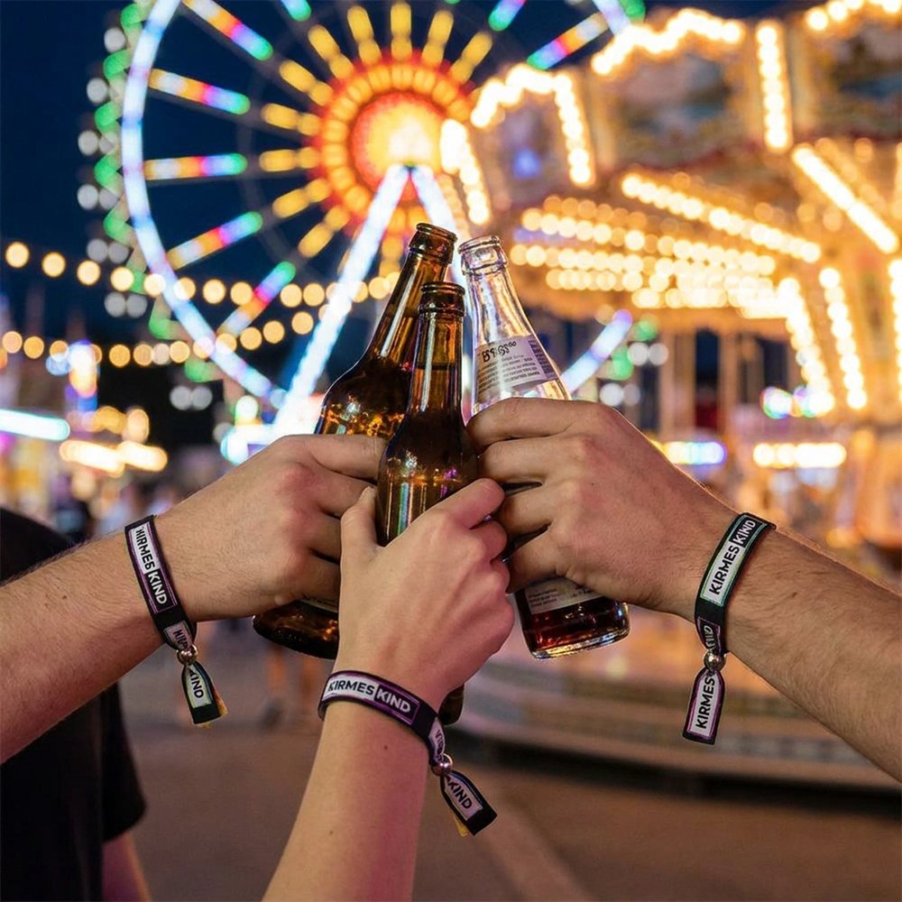 Freunde stoßen auf der Kirmes an und tragen Kirmeskind-Bändchen