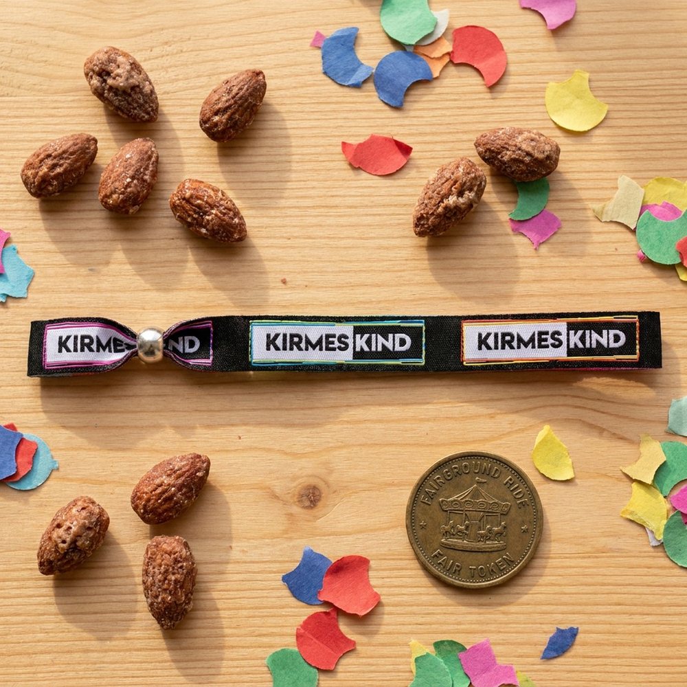 Kirmeskind-Bändchen flach auf Holztisch mit gebrannten Mandeln